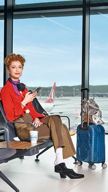 a passenger waiting for their flight with their carry-on luggage